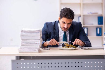 Téléchargez les photos : Jeune employé masculin mangeant réveil - en image libre de droit