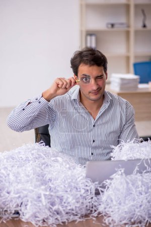Photo for Young businessman employee and a lot of cut papers at workplace - Royalty Free Image