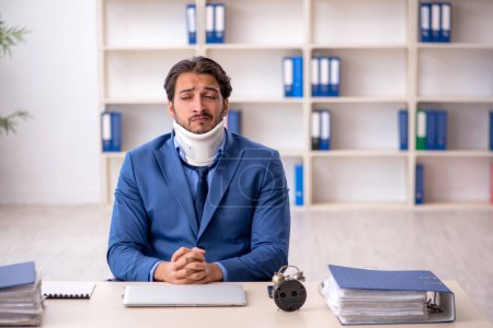 Téléchargez les photos : Jeune homme d'affaires employé après un accident assis sur le lieu de travail - en image libre de droit