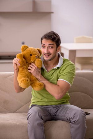 Photo for Young male student with toy bear at home - Royalty Free Image