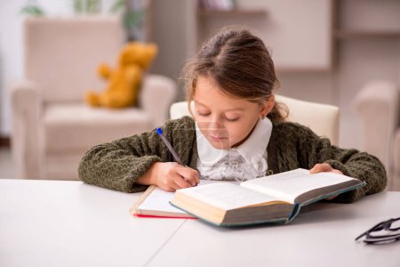Foto de Joven niña pequeña estudiando en casa - Imagen libre de derechos