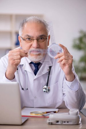 Foto de Viejo doctor sosteniendo goniómetro en el hospital - Imagen libre de derechos