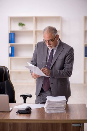 Téléchargez les photos : Vieil homme d'affaires employé travaillant dans le bureau - en image libre de droit