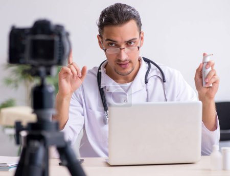 Téléchargez les photos : Le jeune médecin masculin enregistre une vidéo pour son blog - en image libre de droit