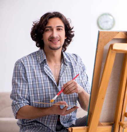 Foto de El joven guapo disfrutando de la pintura en casa - Imagen libre de derechos