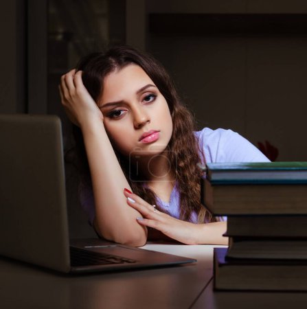 Photo for The young female student preparing for exams late at home - Royalty Free Image