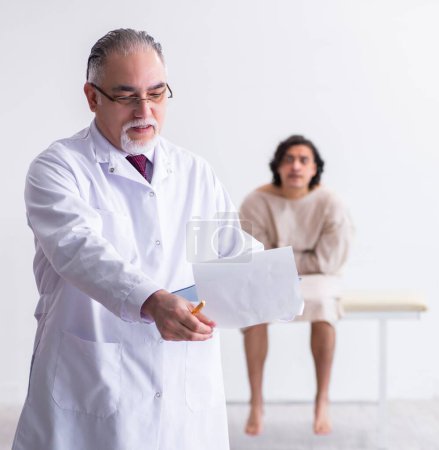 Téléchargez les photos : Le médecin psychiatre homme âgé examinant le jeune patient - en image libre de droit