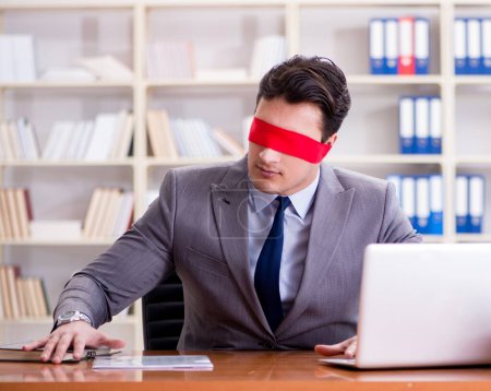 Foto de El hombre de negocios con los ojos vendados sentado en el escritorio en la oficina - Imagen libre de derechos