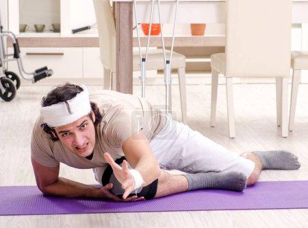 Foto de El joven herido haciendo ejercicios en casa - Imagen libre de derechos