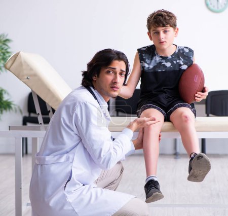 Téléchargez les photos : Le garçon joueur de football américain visitant jeune médecin traumatologis - en image libre de droit