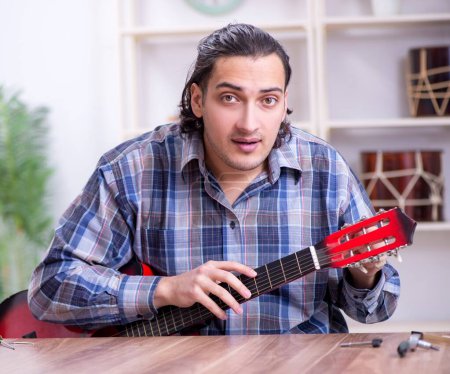Téléchargez les photos : Le jeune réparateur beau réparateur de guitare - en image libre de droit