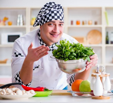Téléchargez les photos : Le jeune cuisinier masculin travaillant dans la cuisine - en image libre de droit