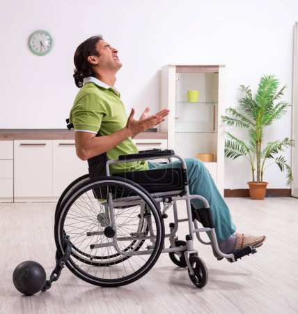 Foto de El joven hombre inválido en silla de ruedas sufriendo en casa - Imagen libre de derechos