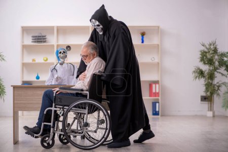 Téléchargez les photos : Vieux patient masculin en fauteuil roulant visitant deux médecins du diable - en image libre de droit