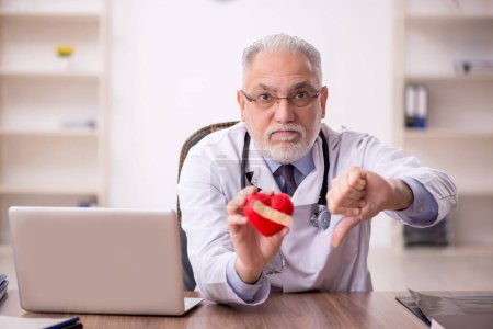 Téléchargez les photos : Vieux cardiologue tenant un modèle cardiaque - en image libre de droit