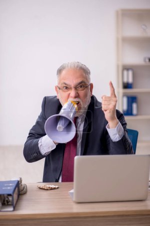 Photo for Old businessman employee holding magaphone in the office - Royalty Free Image