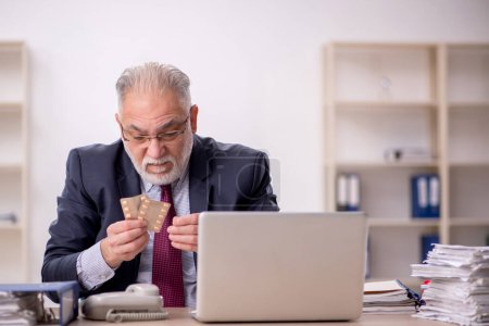 Foto de Viejo empleado de negocios sintiéndose mal en la oficina - Imagen libre de derechos
