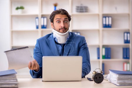 Photo for Young businessman employee after accident sitting at workplace - Royalty Free Image