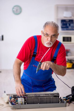 Foto de Viejo reparador masculino reparando aire acondicionado - Imagen libre de derechos