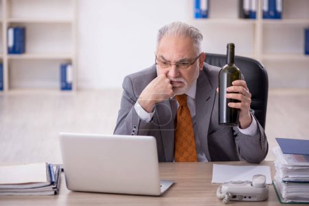 Photo for Old employee drinking alcohol at workplace - Royalty Free Image