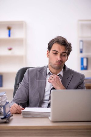 Foto de Joven empleado descontento con el exceso de trabajo en la oficina - Imagen libre de derechos
