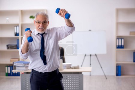 Foto de Viejo empleado masculino haciendo ejercicios deportivos durante el descanso - Imagen libre de derechos