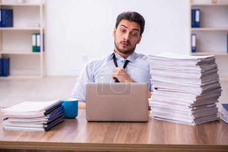 Téléchargez les photos : Jeune employé masculin mécontent du travail excessif au bureau - en image libre de droit