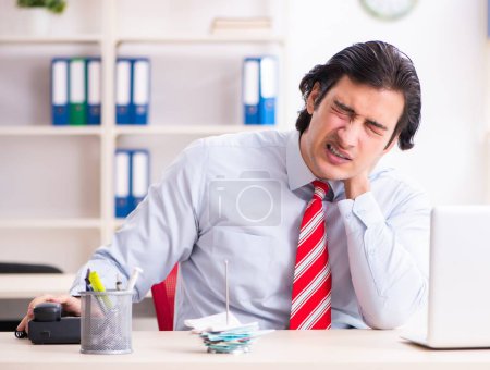 Photo for The young male employee suffering in the office - Royalty Free Image