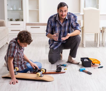 Photo for The young father repairing skateboard with his son at home - Royalty Free Image