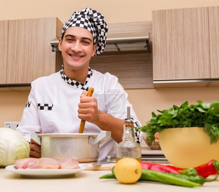 Téléchargez les photos : Le jeune chef travaillant dans la cuisine - en image libre de droit