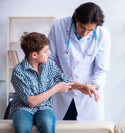 Foto de El niño herido de la mano visitando al joven médico masculino - Imagen libre de derechos