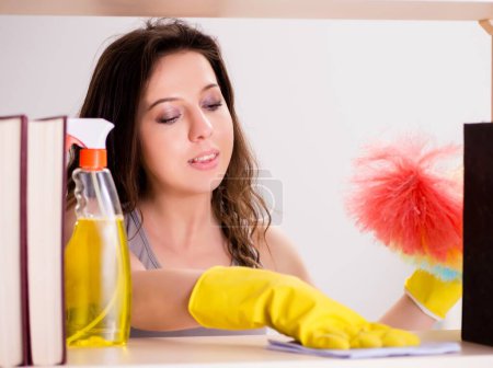 Téléchargez les photos : La femme nettoie la poussière de la bibliothèque - en image libre de droit