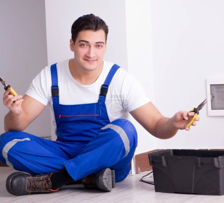 Foto de El joven electricista trabajando en zócalo en casa - Imagen libre de derechos