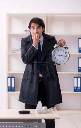 Foto de El joven empleado masculino en la oficina en concepto de gestión del tiempo - Imagen libre de derechos