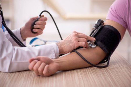 Téléchargez les photos : Vieux médecin mesurant la pression artérielle des jeunes patients - en image libre de droit
