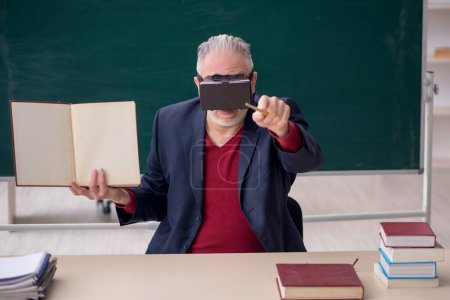 Téléchargez les photos : Old teacher wearing virtual glasses in the classroom - en image libre de droit