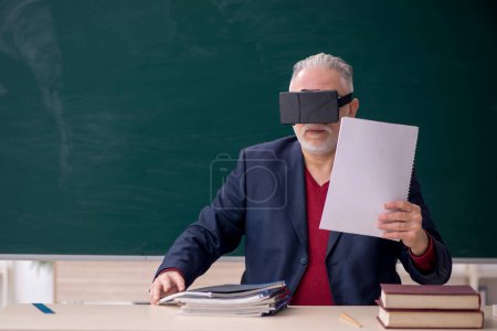 Téléchargez les photos : Old teacher wearing virtual glasses in the classroom - en image libre de droit