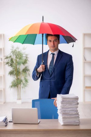 Photo for Young employee holding an umbrella at workplace - Royalty Free Image