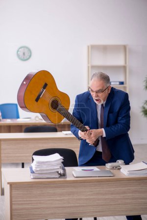 Photo for Old employee playing guitar in the office - Royalty Free Image