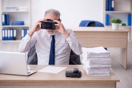 Téléchargez les photos : Old businessman employee wearing virtual glasses in the office - en image libre de droit