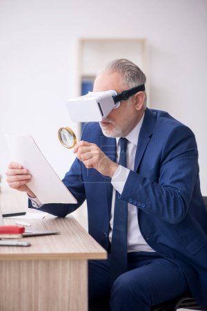 Foto de Old businessman employee wearing virtual glasses in the office - Imagen libre de derechos
