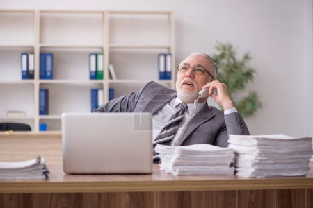 Téléchargez les photos : Vieil homme d'affaires employé et trop de travail sur le lieu de travail - en image libre de droit
