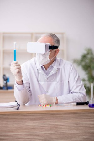 Téléchargez les photos : Old chemist wearing virtual glasses at the lab - en image libre de droit