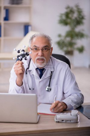 Téléchargez les photos : Ancien médecin conférencier tenant modèle moléculaire - en image libre de droit