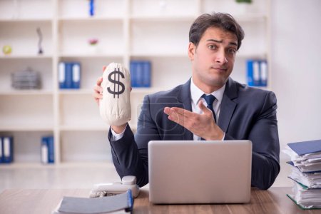 Photo for Young employee holding moneybag at workplace - Royalty Free Image