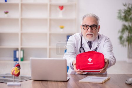 Téléchargez les photos : Vieux médecin ambulancier tenant sac de premiers soins - en image libre de droit