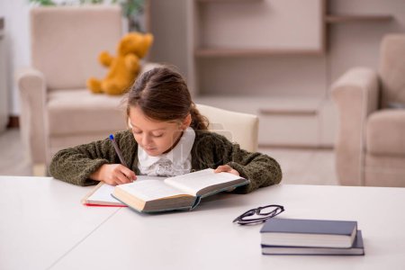 Foto de Joven niña pequeña estudiando en casa - Imagen libre de derechos