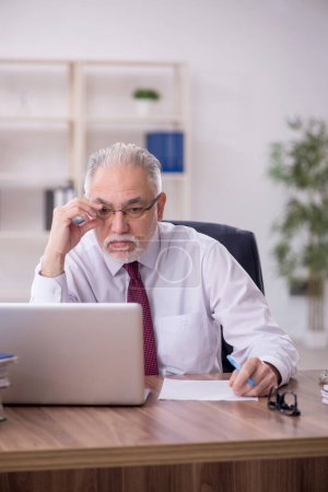 Téléchargez les photos : Vieil homme d'affaires employé et trop de travail dans le bureau - en image libre de droit