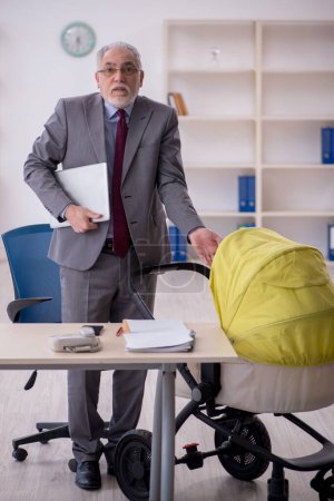 Foto de Un viejo empleado de negocios que cuida a un recién nacido en la oficina - Imagen libre de derechos