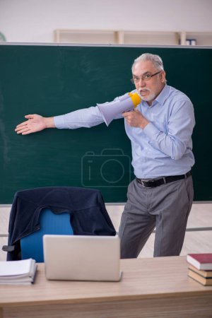 Photo for Old teacher holding megaphone in the classroom - Royalty Free Image